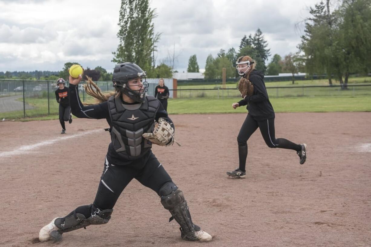 Battle Ground catcher Grace Stillman throws to first base as pitcher Mallory Meyer runs to cover home plate during an infield drill during a recent practice at Battle Ground High School. Stillman was named the 4A Greater St. Helens League MVP while Meyer was named pitcher of the year.