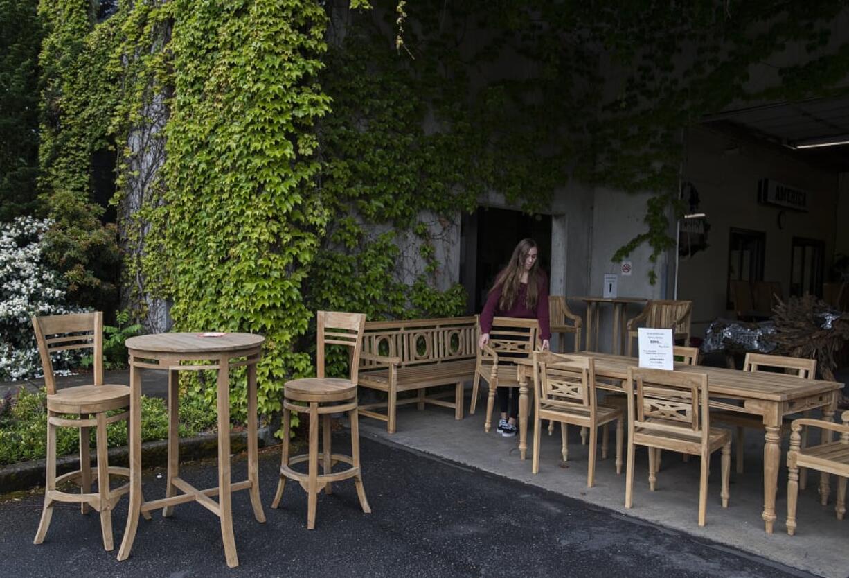 Taylor Thompson of America the Beautiful Dreamer helps arrange a display of teak outdoor furniture while preparing for customers in the Sifton area.