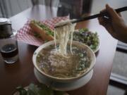 A bowl of Pho Chin Nam, clockwise from center, is served with a Vietnamese coffee with sweetened condensed milk, a grilled pork Banh Mi and beef short ribs at UnPhogettable.