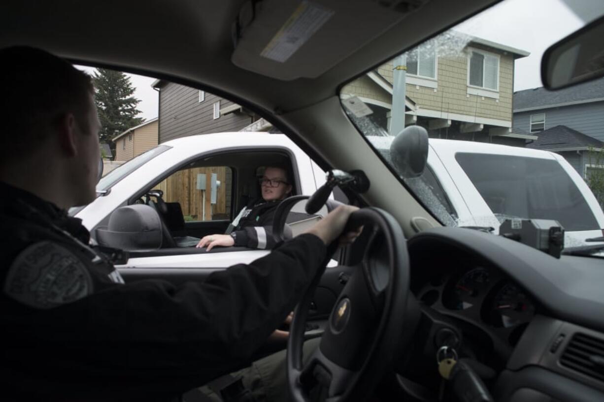 Clark County Sheriff’s deputies Alex O’Hearn, foreground, and Melissa Sager compare notes while searching for a stolen car in the Orchards area of Vancouver. The deputies are two of the department’s newest hires.