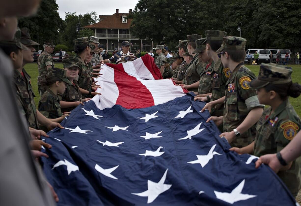 Volunteers lend a hand as they help to unfold and hoist the Garrison Flag during the 2019 Memorial Day service at Fort Vancouver National Historic Site on Monday.