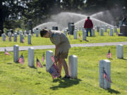 David Kilway, 13, of Boy Scouts Troop 370 helps prepare for Memorial Day by placing flags on graves Thursday afternoon at Vancouver Barracks Post Cemetery.