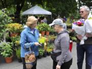 Pam Coffer, from left, Dorothy Parkin and John Parkin examine their purchases from N & M Herb Nursery at the Vancouver Farmers Market on Sunday. The plant booth is on a corner of Market Square, an open intersection at Eighth and Esther streets where kids can play.