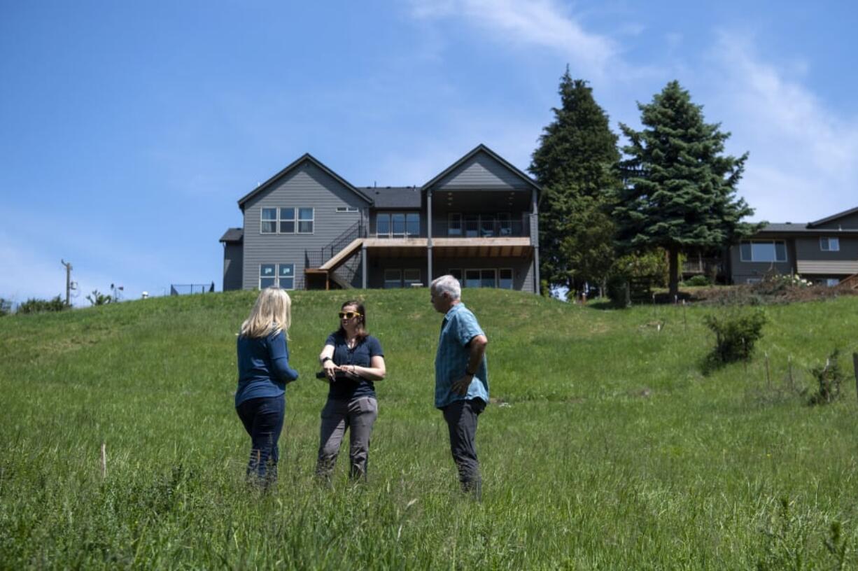 Homeowners Julie Zanzi, left, and John Zanzi talk with Clark Conservation District resource specialist Ashley Smithers on how to use local plants to make a field of grass near their home more environmentally friendly. The Zanzis participated in a six-week class on watershed stewardship that the conservation district offers.