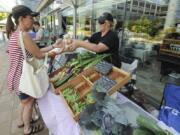 Melissa Leady, left, buys eggs from Heather Lawhead of Blue Dog Farm at the Salmon Creek Farmers’ Market at Legacy Salmon Creek Medical Center in 2016. The market is returning for its 10th year on June 11, and its eighth year at the hospital.