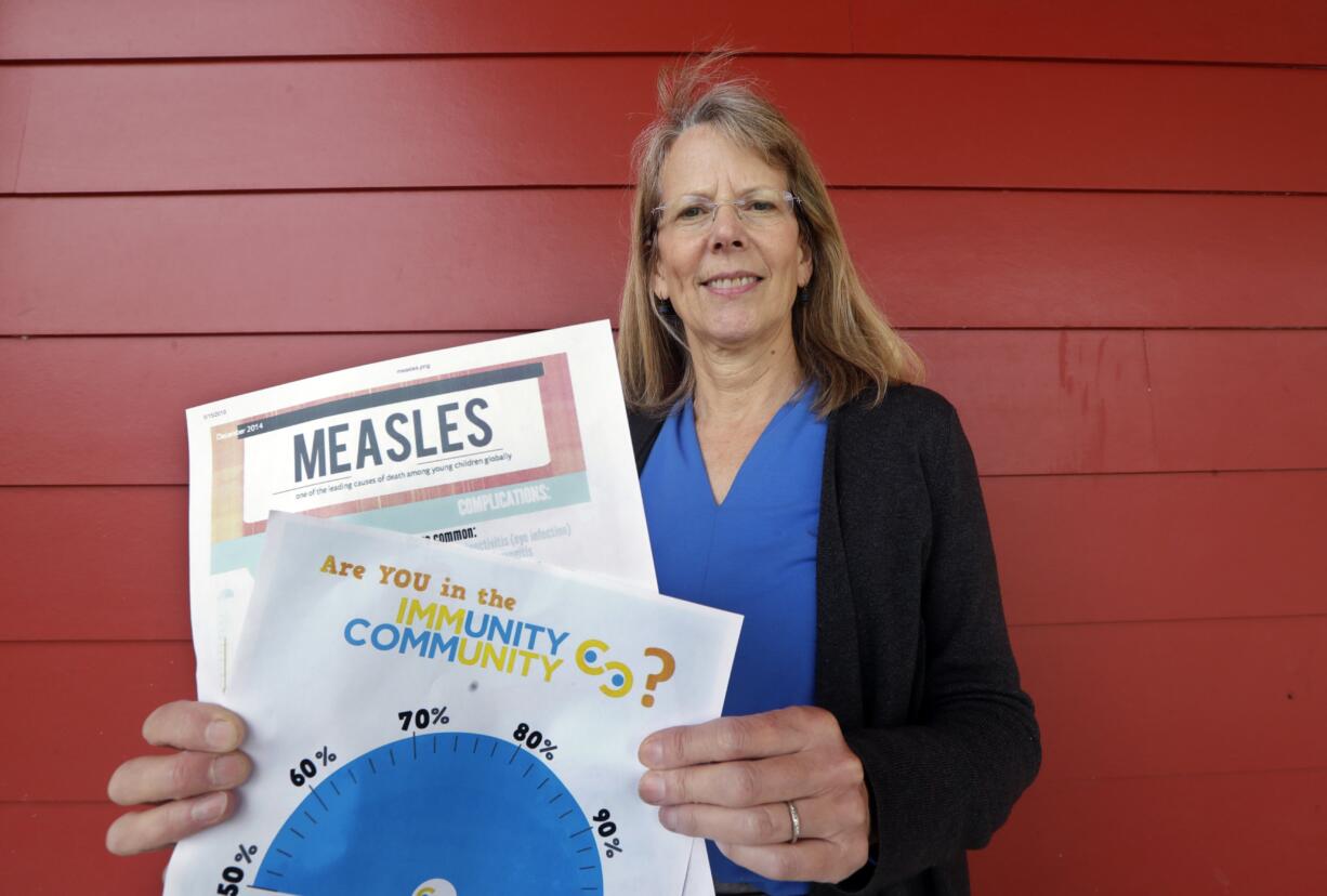 In this photo taken Wednesday, May 15, 2019, Vashon Island High School nurse Sarah Day holds information about measles vaccinations as she poses for a photo in Vashon Island, Wash. Since Day began communal living on Vashon Island more than 20 years ago, the registered nurse has been advocating for getting kids their shots against a loud contingent of anti-vaccine parents in the close-knit community of about 11,000 that's accessible only by ferry, a serene 20-minute ride from Seattle. And it may now be working, thanks to a "perfect storm" of changes being felt on the island, Day said.