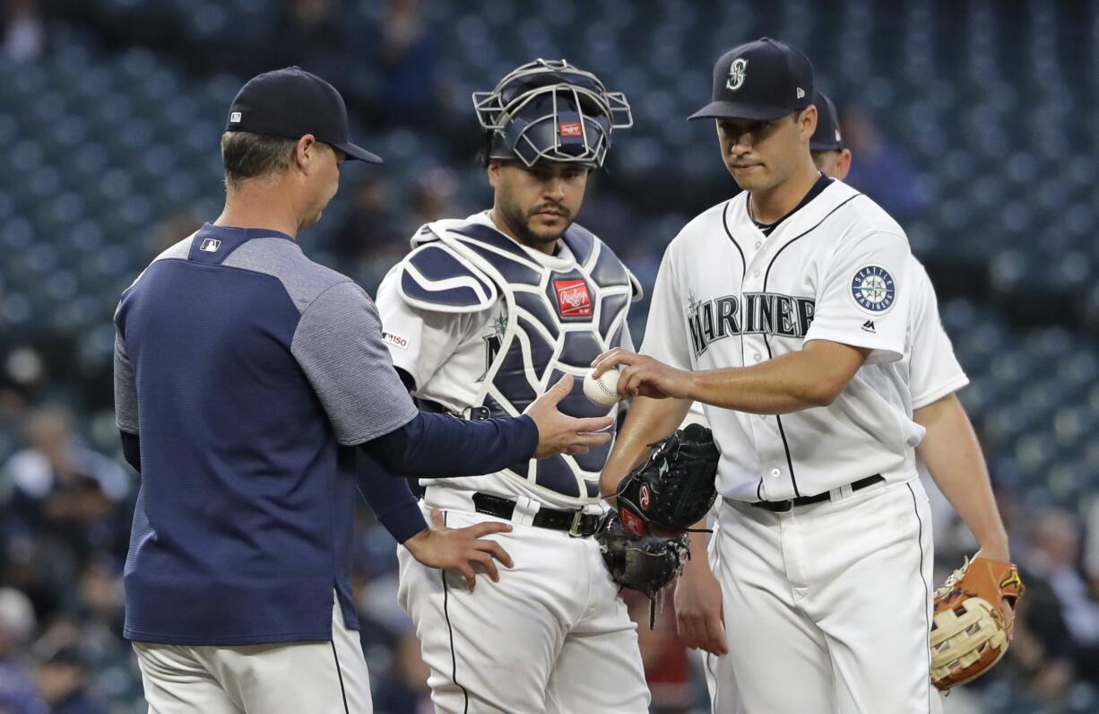 Seattle Mariners starting pitcher Marco Gonzales, right, hands the ball to manager Scott Servais, left, as catcher Omar Narvaez, center, looks on during the fifth inning of a baseball game against the Texas Rangers, Tuesday, May 28, 2019, in Seattle. (AP Photo/Ted S.