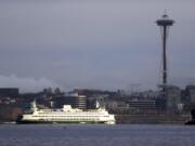 A Washington State ferry heading into Elliott Bay is illuminated by the sun as the city behind remains under clouds in Seattle in 2018.