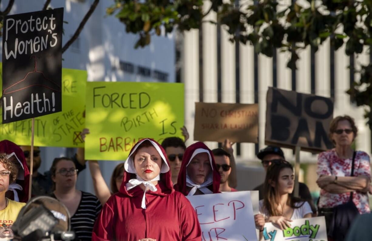 Margeaux Hartline, dressed as a handmaid, protests against a ban on nearly all abortions Tuesday outside the Alabama State House in Montgomery, Ala.