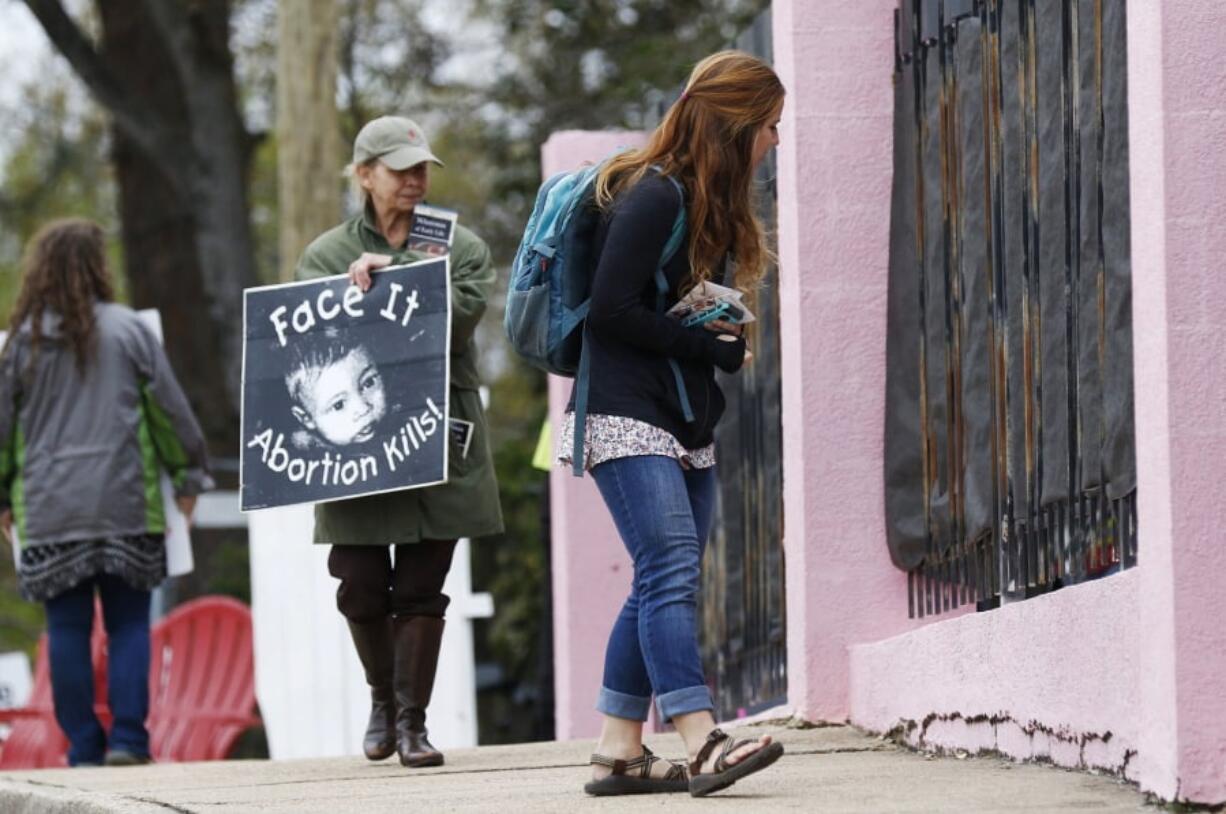 In this March 20, 2018, file photo, anti-abortion sidewalk counselors call out to a woman entering the Jackson Women’s Health Organization’s clinic, the only facility in the state that performs abortions, in Jackson, Miss. A new Mississippi law could make it nearly impossible for most pregnant women to get an abortion there if it survives a court challenge. (AP Photo/Rogelio V.