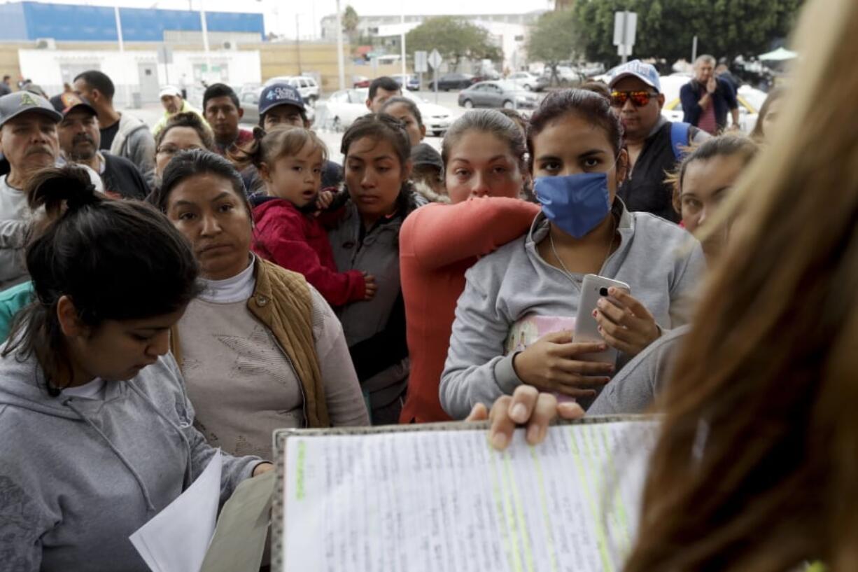 Women in Tijuana, Mexico, look on Oct. 23 as numbers and names are called from a list of asylum-seekers who want to cross the border into the United States.