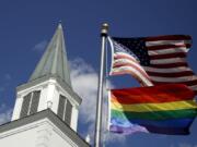 A gay pride rainbow flag flies along with the U.S. flag in front of the Asbury United Methodist Church in Prairie Village, Kan.