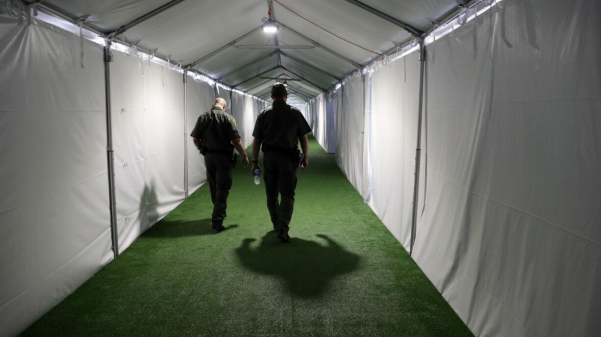 U.S. Border Patrol agents walk down the hallway of a new U.S. Customs and Border Protection temporary facility Thursday near the Donna International Bridge in Donna, Texas. Officials say the site will primarily be used as a temporary site for processing and care of unaccompanied migrant children and families and will increase the Border Patrol’s capacity to process migrant families.