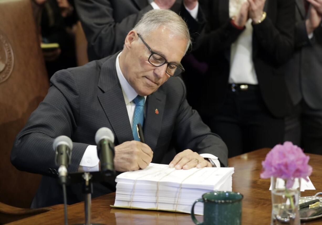 Gov. Jay Inslee signs the state operating budget Tuesday at the Capitol in Olympia. Ted S.