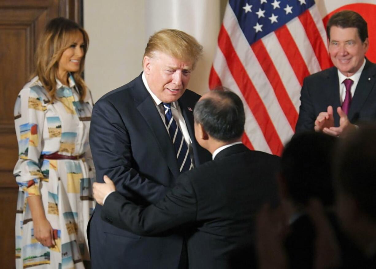 U.S. President Donald Trump, center left, greets SoftBank Group Corp.’s Chief Executive Masayoshi Son, center right, as first lady Melania Trump, left, and U.S. Ambassador to Japan William Hagerty looks on during his meeting with business leaders, in Tokyo, Saturday, May 25, 2019. President Trump is on a four-day state visit in Japan.