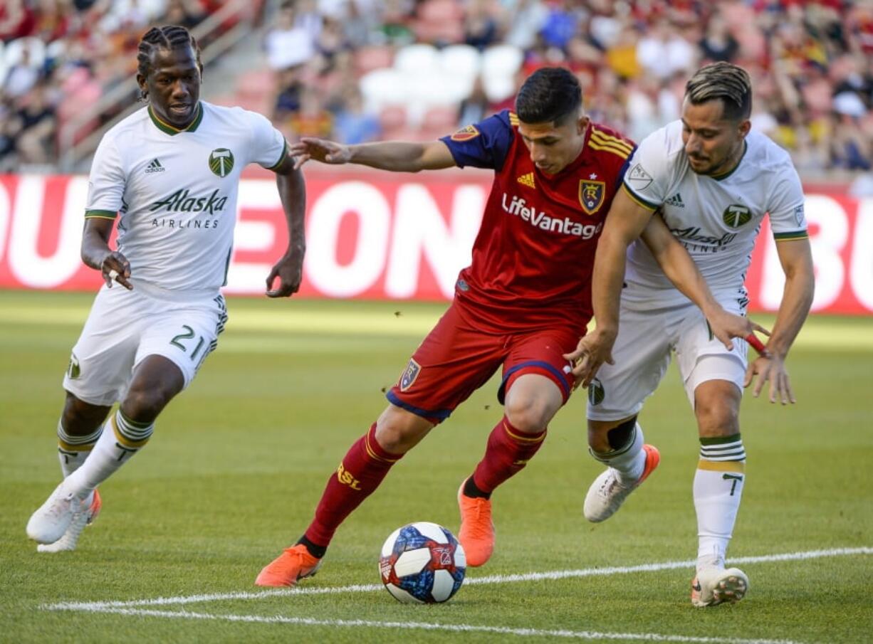 Portland Timbers midfielders Diego Chara (21) and Sebastian Blanco (10) pressure Real Salt Lake forward Jefferson Savarino during an MLS soccer match Saturday, May 4, 2019, in Sandy, Utah.