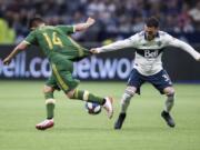 Vancouver Whitecaps’ Russell Teibert, right, grabs the jersey of Portland Timbers’ Andres Flores as he tries to slow Flores down during the second half of an MLS soccer match Friday, May 10, 2019, in Vancouver, British Columbia.