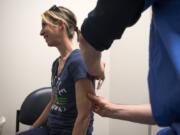 Julie Scordino of Camas holds still as registered nurse Kent Slawson administers the MMR vaccine during a free vaccination clinic offered by Legacy Medical Group in Vancouver. Legacy offered vaccination MMR vaccination clinics in March as a low barrier opportunity for vaccinations.