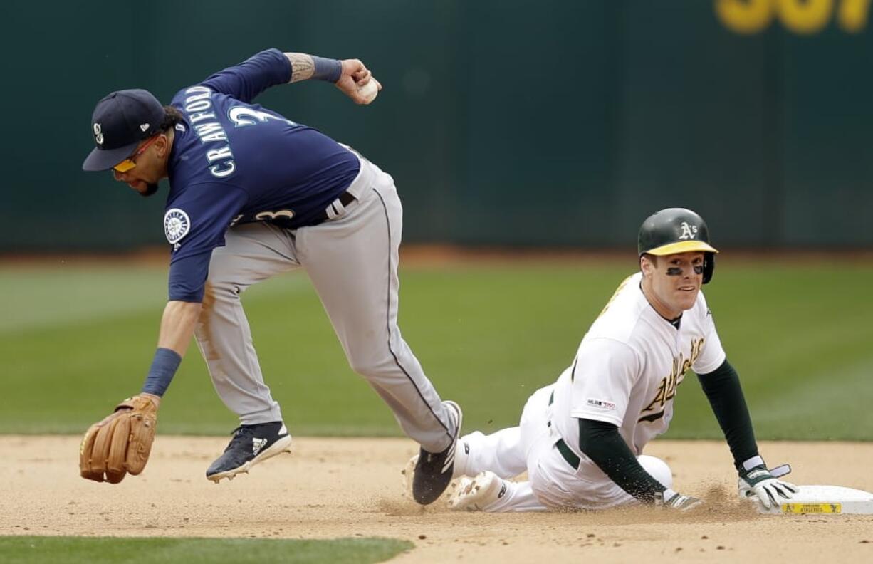 Oakland Athletics’ Mark Canha, right, breaks up a double play with Seattle Mariners’ J.P. Crawford, left, in the seventh inning of a baseball game Sunday, May 26, 2019, in Oakland, Calif.