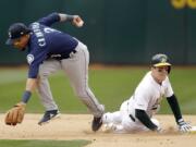 Oakland Athletics’ Mark Canha, right, breaks up a double play with Seattle Mariners’ J.P. Crawford, left, in the seventh inning of a baseball game Sunday, May 26, 2019, in Oakland, Calif.