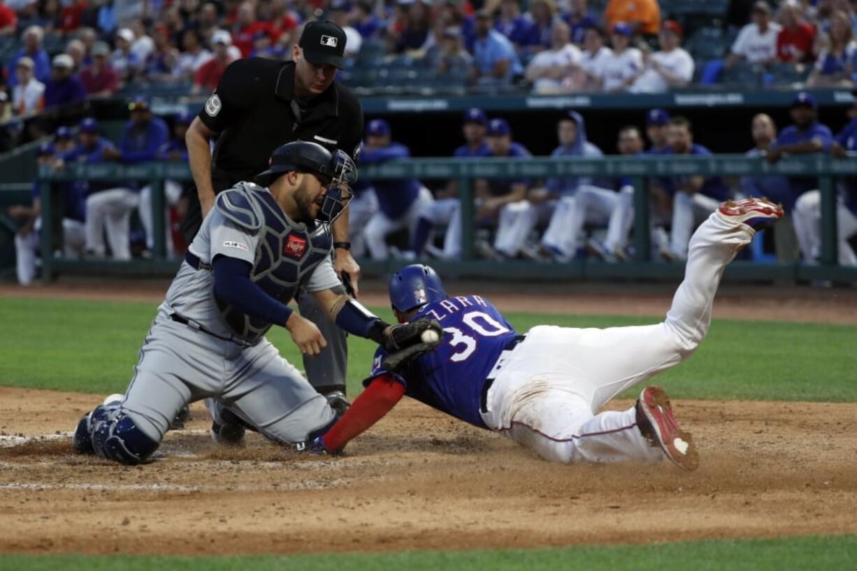 Seattle Mariners catcher Omar Narvaez (22) attempts the tag as Texas Rangers’ Nomar Mazara (30) scores on a sacrifice fly by Asdrubal Cabrera in the fourth inning of a baseball game in Arlington, Texas, Tuesday, May 21, 2019. Umpire Andy Fletcher watches the play develop.