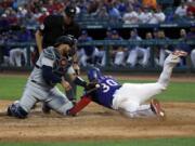 Seattle Mariners catcher Omar Narvaez (22) attempts the tag as Texas Rangers’ Nomar Mazara (30) scores on a sacrifice fly by Asdrubal Cabrera in the fourth inning of a baseball game in Arlington, Texas, Tuesday, May 21, 2019. Umpire Andy Fletcher watches the play develop.