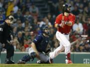 Boston Red Sox’s Mitch Moreland, right, follows through on his three-run home run in front of Seattle Mariners’ Tom Murphy during the third inning of a baseball game in Boston, Friday, May 10, 2019.