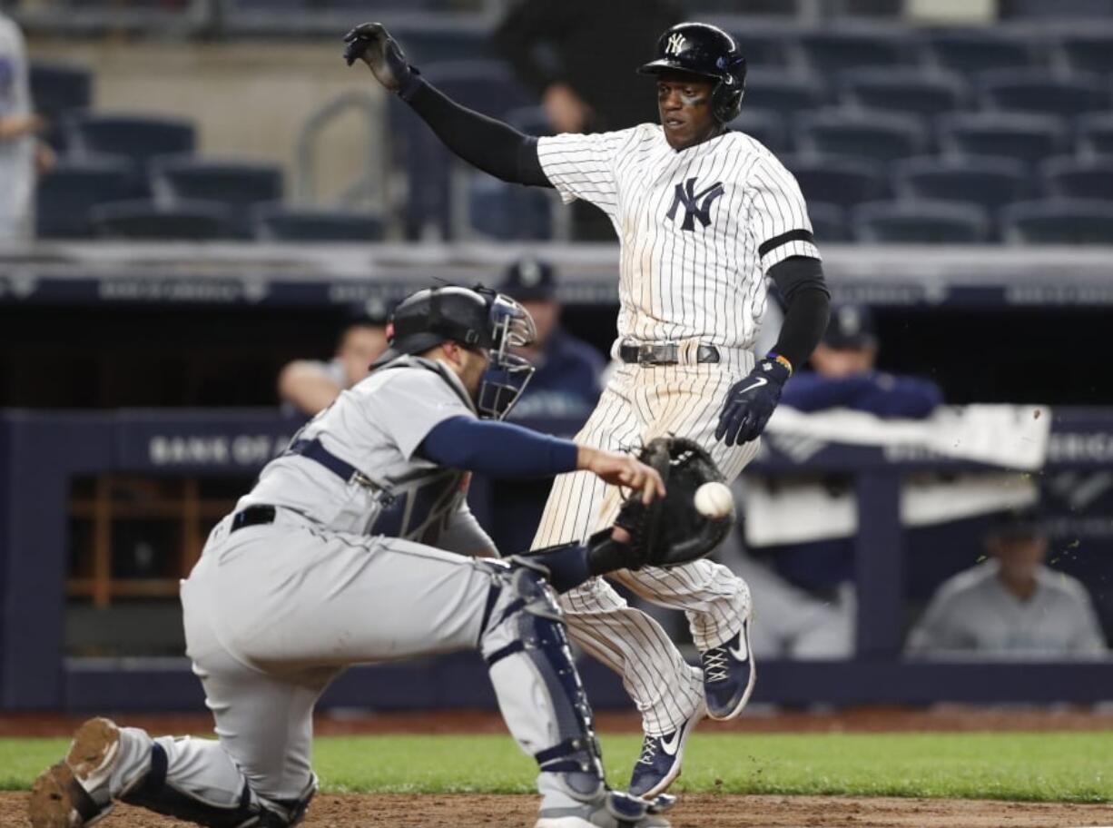 Seattle Mariners catcher Tom Murphy, left, tries to corral the throw as New York Yankees’ Cameron Maybin runs home to score on a game-winning RBI single by DJ LeMahieu during the ninth inning of a baseball game, Tuesday, May 7, 2019, in New York. The Yankees won 5-4.