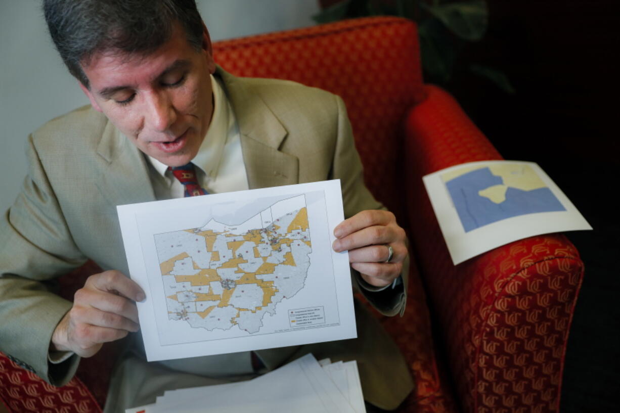 FILE - In this April 11, 2019 file photo, David Niven, a professor of political science at the University of Cincinnati holds a map displaying the wide disparity of Ohio congressional district office locations, with orange locations representing areas whose office are found outside it’s own district’s bounds, in Cincinnati. A federal court ruled Friday, May 3 that Ohio’s congressional map is unconstitutional and ordered a new one be drawn for the 2020 elections.