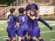 Columbia River's Julian Villa-Salas, top, jumps into a pile centered around Aaron Espinosa and Jake Connop after Espinosa' 35th-minute goal in a 2A State first-round game Tuesday at Chieftain Stadium. Columbia River won 3-1.