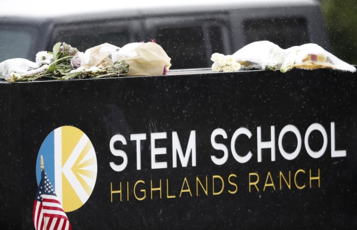 A light snow covers bouquets of flowers placed on the sign for STEM School Highlands Ranch following Tuesday’s shooting, in Highlands Ranch, Colo., Thursday, May 9, 2019.