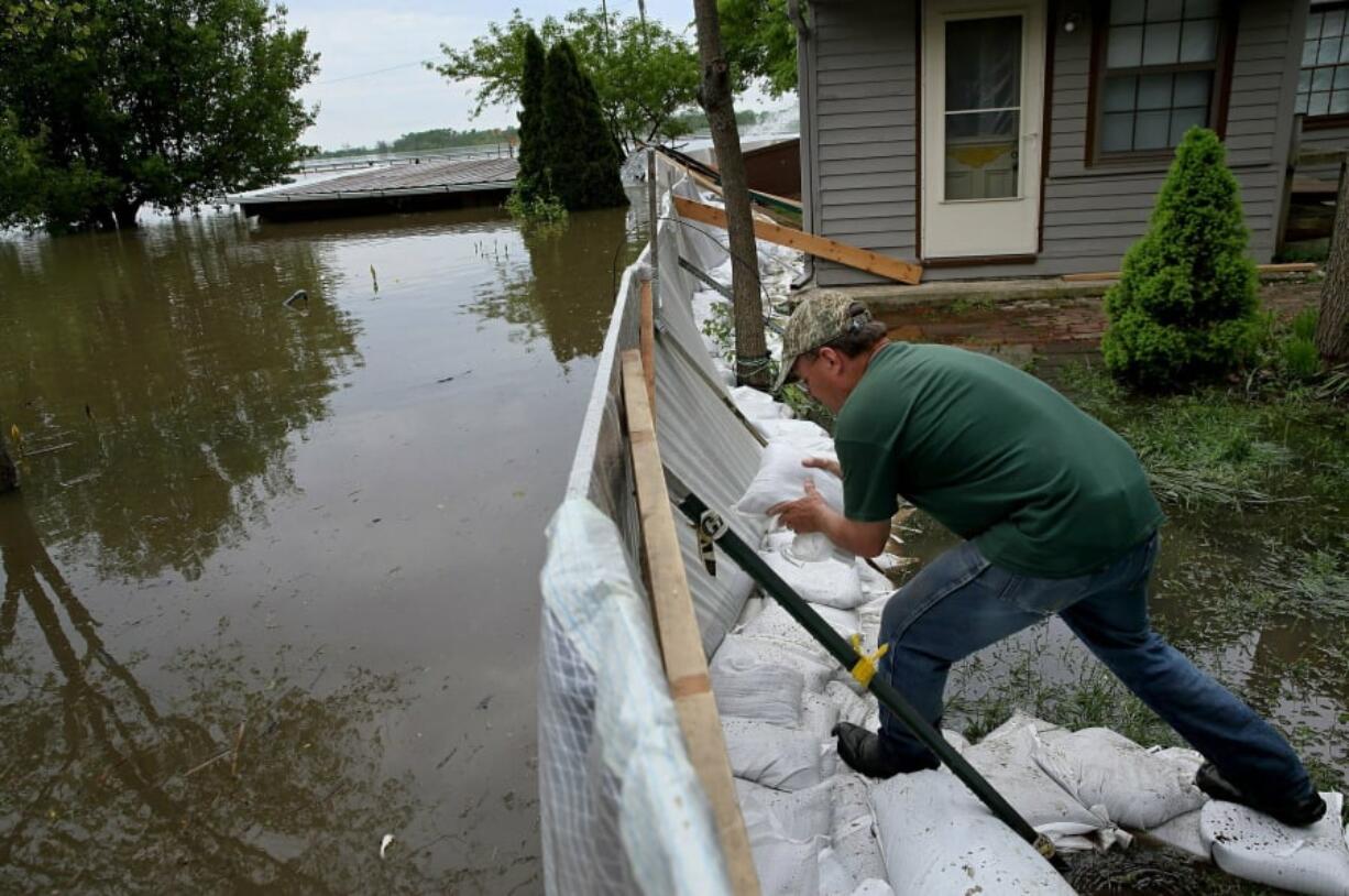 Alley Ringhausen uses sandbags to shore up the wall he and other volunteers built around the Riverview House in Elsah, Ill., as floodwater from the Mississippi River seeps through a makeshift barrier on Monday, May 6, 2019. (David Carson/St.