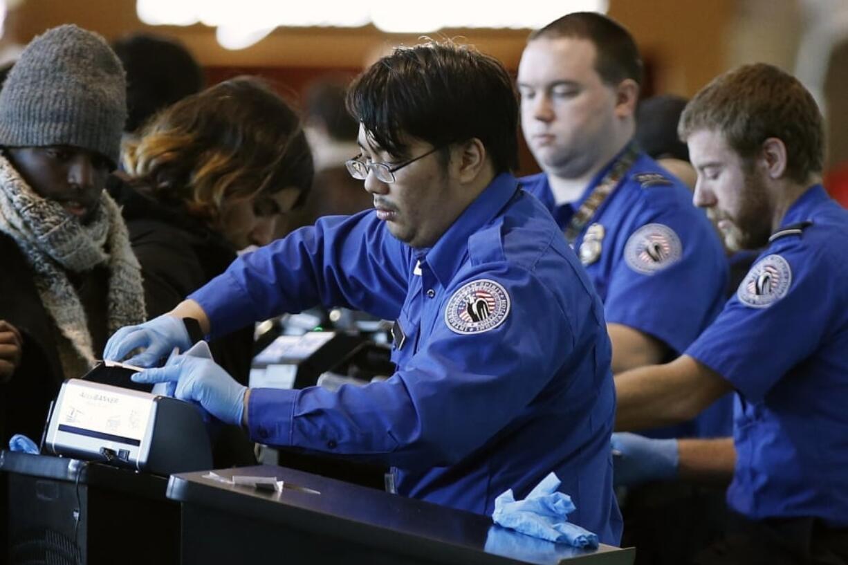 FILE - In this Dec. 23, 2018 file photo, Transportation Security Administration officers check boarding passes and identification at Logan International Airport in Boston. A House panel is divided over the Trump administration’s move to send TSA employees from airports to the US-Mexico border. Republican lawmaker says the move shows the severity of the crisis on the border, where waves of migrants are arriving. But a Democratic committee chairman says the administration is manufacturing a crisis.