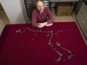 Sterling Nesbitt, an assistant professor of geobiology, sits for a photo March 28 next to the fossilized bones of Suskityrannus hazelae, a miniature adult Tyrannosaurus dinosaur relative, in Blacksburg, Va. He found some of the original fossils when he was 16 years old.