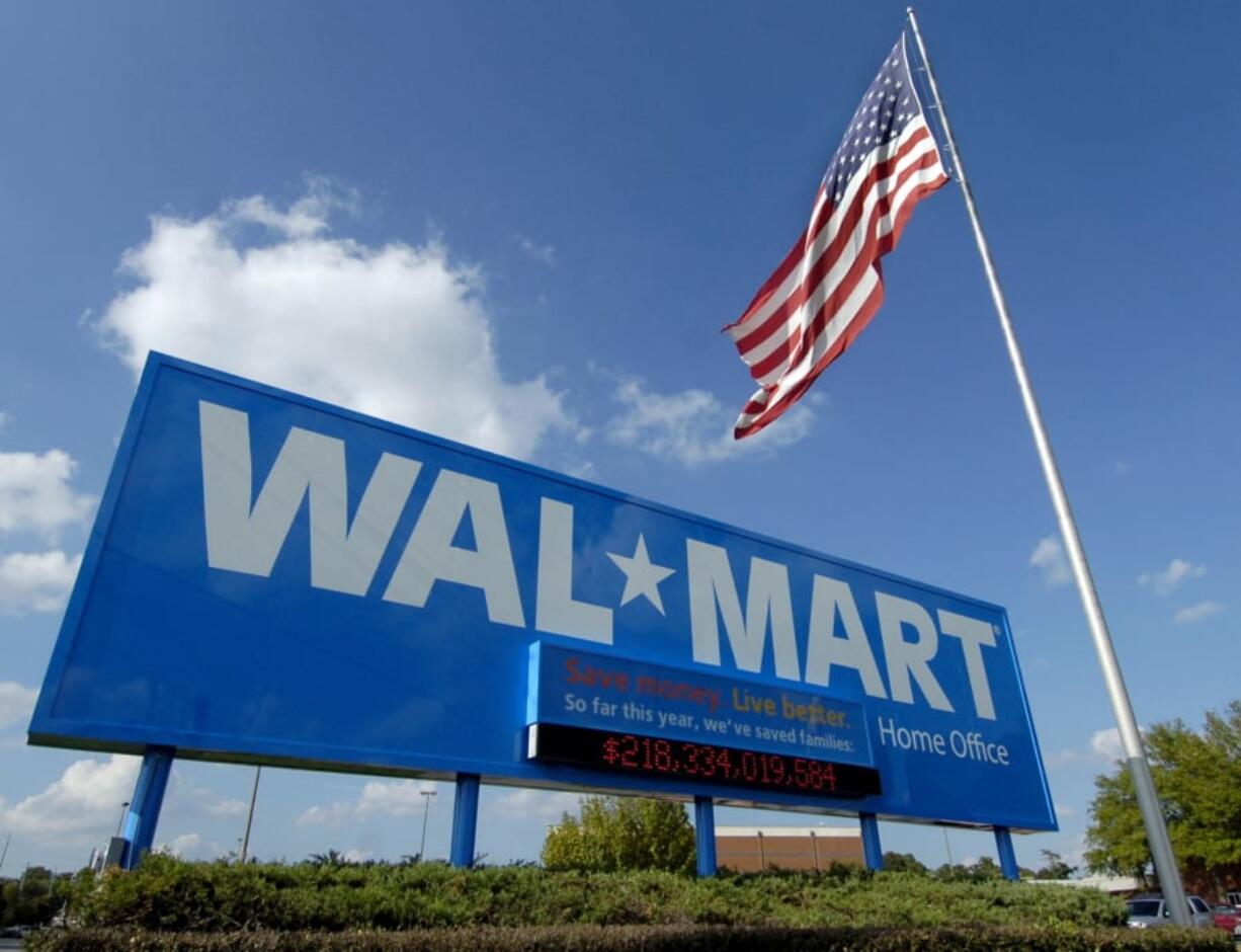 FILE - In this Oct. 5, 2007, file photo, an American flag flies in front of the Walmart Stores Inc. headquarters in Bentonville, Ark. Walmart said Wednesday, May 8, 2019, that it will raise the minimum age for tobacco products and e-cigarettes to 21 in an effort to combat tobacco sales to minors. The world’Äôs largest retailer says the new rule will take effect in July, and will also include its Sam’Äôs Club warehouse stores. (AP Photo/April L.