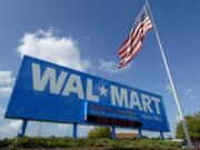 FILE - In this Oct. 5, 2007, file photo, an American flag flies in front of the Walmart Stores Inc. headquarters in Bentonville, Ark. Walmart said Wednesday, May 8, 2019, that it will raise the minimum age for tobacco products and e-cigarettes to 21 in an effort to combat tobacco sales to minors. The world’Äôs largest retailer says the new rule will take effect in July, and will also include its Sam’Äôs Club warehouse stores. (AP Photo/April L.