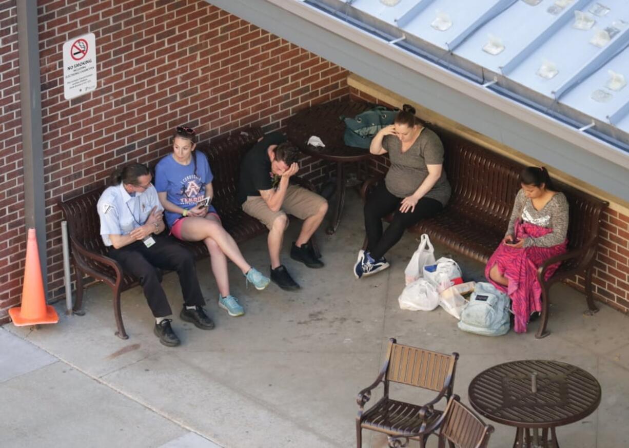 In this Wednesday, May 15, 2019 photo, people wait as authorities investigate the scene of a shooting at the Valley Transit Center in Appleton, Wis. A firefighter responding to a medical emergency was killed in the shooting at a Wisconsin bus station that left several others injured, officials said.