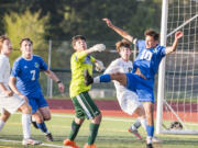 Peninsula goalkeeper Yzahir Cornelio, yellow, looks for a loose ball as Mountain View's Andres Lopez-Garcia, 10, makes a challenge for it in a 3A bi-district boys soccer game Tuesday at McKenzie Stadium. Peninsula won 2-1.