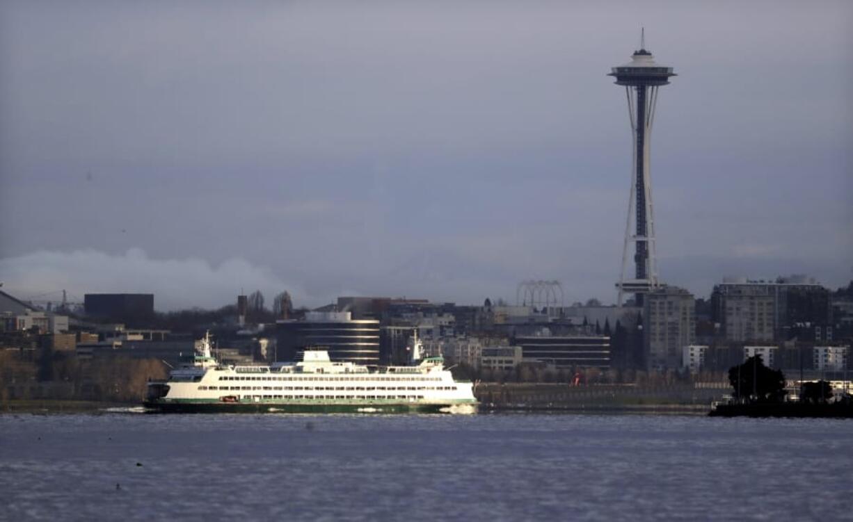 A Washington ferry heading into Elliott Bay is illuminated by the sun as the city behind remains under clouds on Dec. 27 in Seattle.