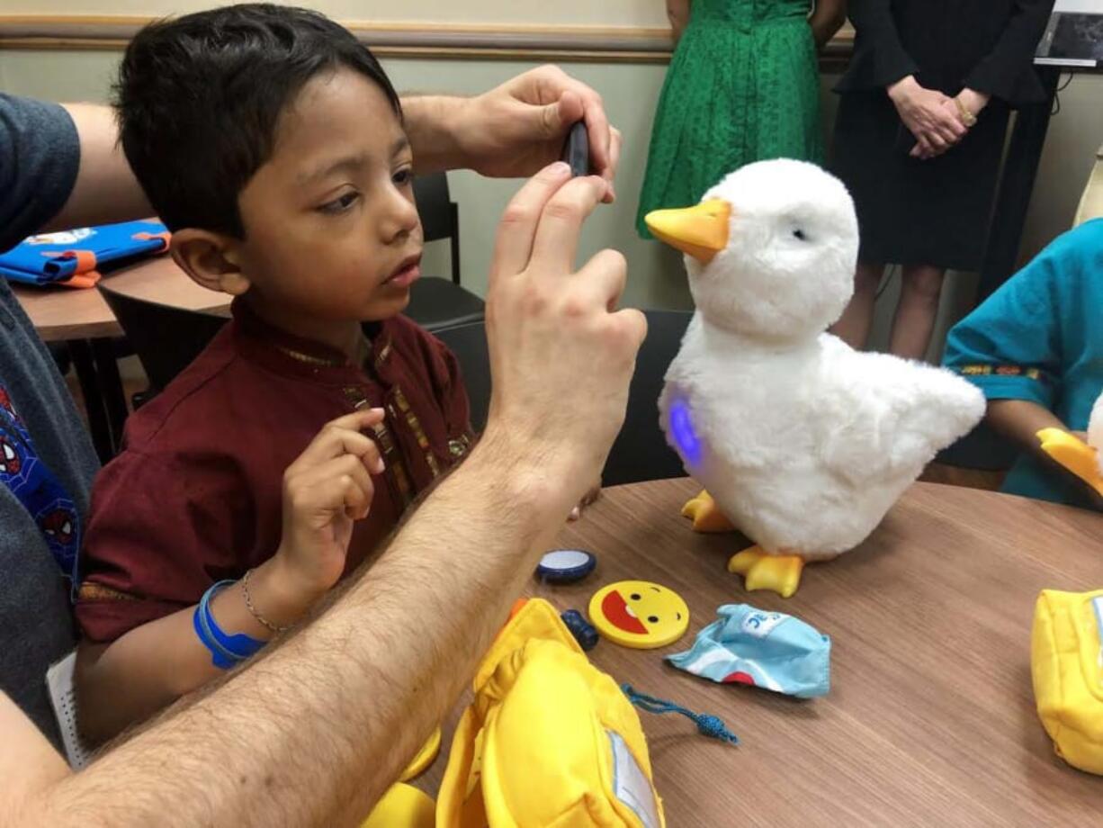 Savi Abdallah-Sinha, a 4-year-old battling leukemia, interacts with “My Special Aflac Duck,” a robotic duck designed to provide sick children with a companion and help them communicate with adults, in Washington, D.C.