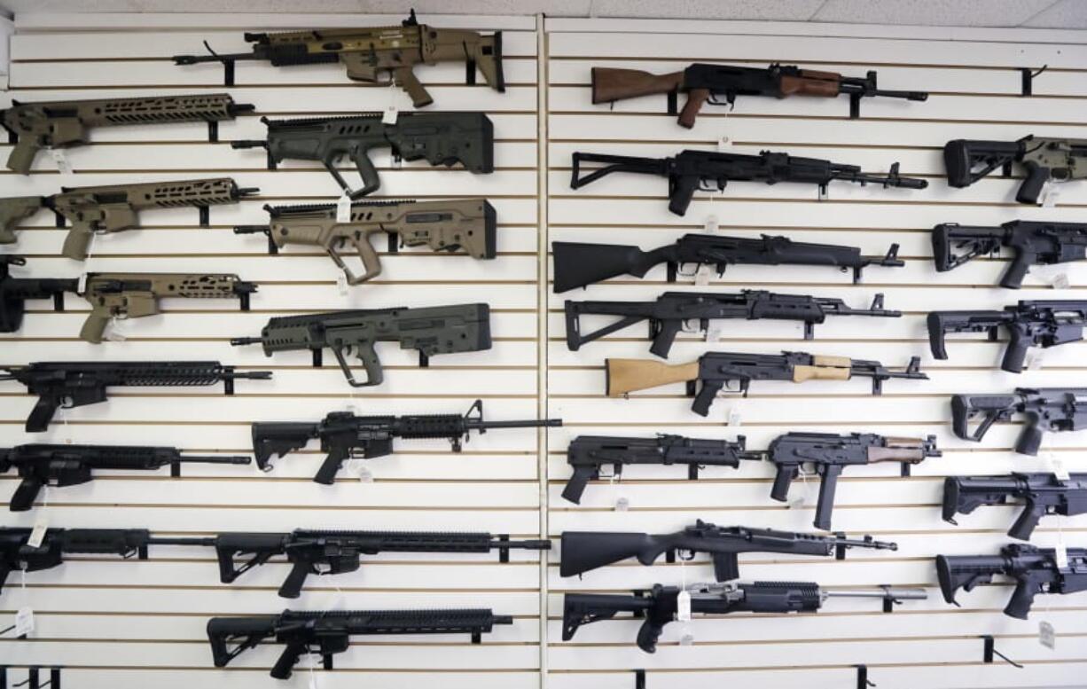 Semi-automatic rifles fill a wall in October at a gun shop in Lynnwood. On Monday, much of Initiative 1639 will go into effect: People wanting to purchase semi-automatic assault rifles will have to undergo an enhanced background check, prove that they’ve undergone firearms safety training and could face criminal liability for not securing firearms.