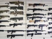 Semi-automatic rifles fill a wall in October at a gun shop in Lynnwood. On Monday, much of Initiative 1639 will go into effect: People wanting to purchase semi-automatic assault rifles will have to undergo an enhanced background check, prove that they’ve undergone firearms safety training and could face criminal liability for not securing firearms.