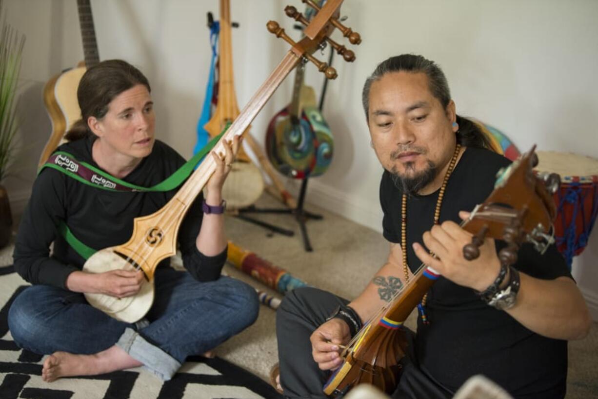 Apprentice Courtney Elton of Brush Prairie, left, has been studying the dramyen, or Tibetan mandolin, with Vancouver resident Tamding Tsetan. Elton has long loved Tibetan culture, she said, so it was fortuitous when she happened to meet Tsetan up at Lucia Falls — when he was trying out a new dramyen.