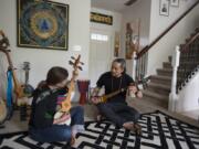 Apprentice Courtney Elton of Brush Prairie, left, studies the dramyen, or Tibetan mandolin, at the Vancouver home of her instructor, Tamding Tsetan. He grew up in Tibet but fled, and came to America in 2013.