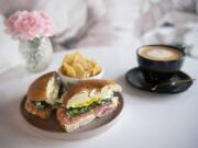 The salmon breakfast sandwich at Presso Coffee Kitchen. The sandwich is served on a plain bagel with a fried egg, smoked salmon, pickled onions, spinach and chive cream cheese.