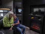 Edith Perrone, left, and her daughter, Glenda Peck, enjoy the electric fireplace in Perrone’s new trailer. As rent prices increased, Peck decided to buy a 26-foot recreational vehicle and move into a park. Her mother followed suit a few years later, putting her large family home on the market and purchasing a new 37-foot trailer.