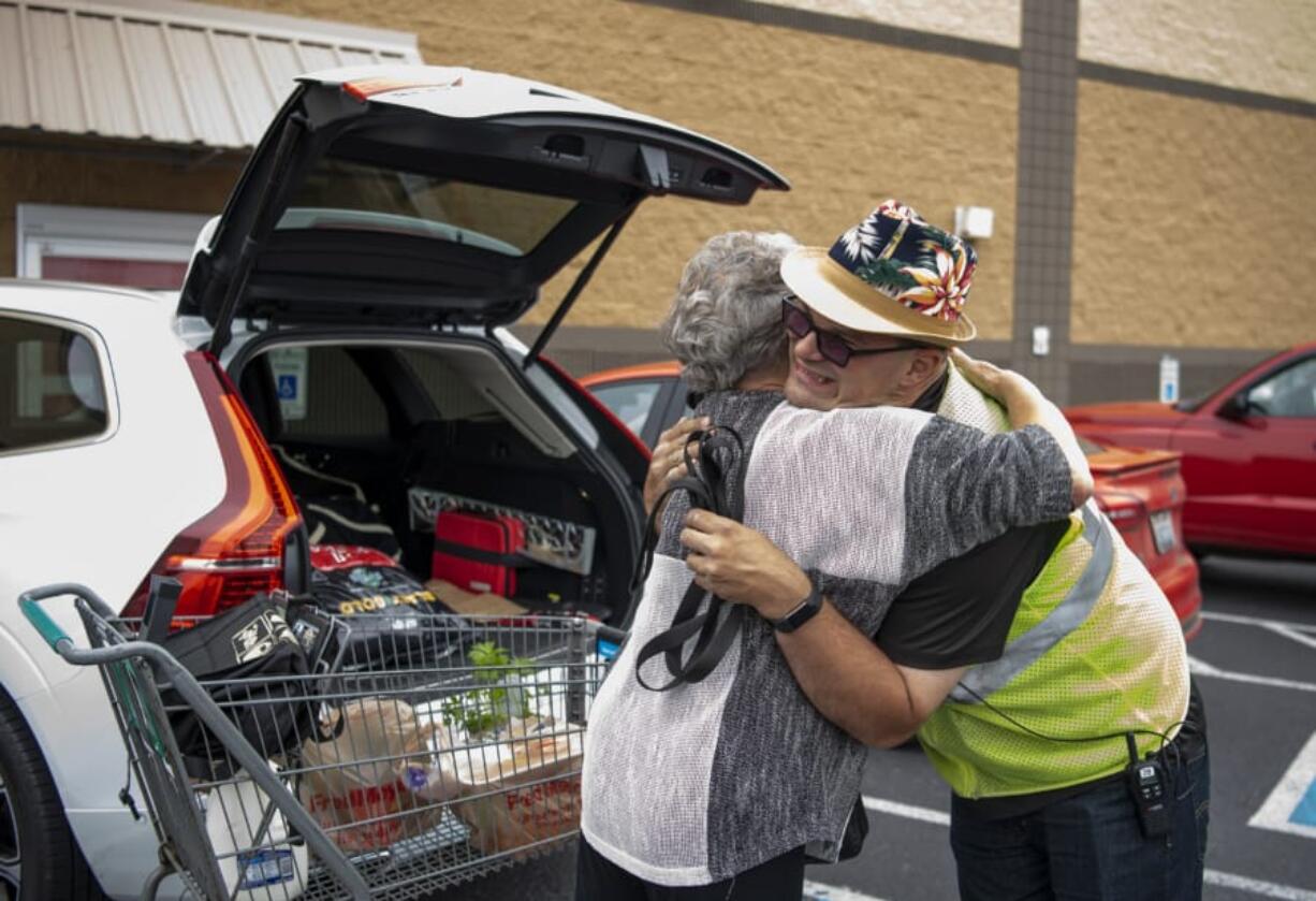 Joyce Stuck of La Center, left, embraces Ben Lemons of Battle Ground during his shift at Fred Meyer in Battle Ground on Wednesday. Lemons has worked at the store seven years, and often greets his regular customers with a hug and big smile.