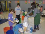 Gause Elementary School students Olive Krysak, from left, and Hudson Leifsen help Michelle Picinich, environmental outreach specialist for the Green Schools program, sort trash. The school joined the Clark County Green Schools program this year, and saved thousands by cutting down on waste and increasing recycling.