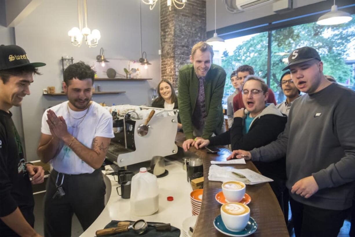 The crowd gathers around two lattes before voting during a latte art competition at Compass Coffee in Vancouver.