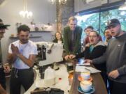 The crowd gathers around two lattes before voting during a latte art competition at Compass Coffee in Vancouver.